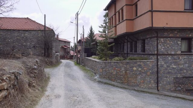 Mountain Lodges traditional village settlement with stone-built houses and red tile rooftops in Agios Athanasios, Greece.