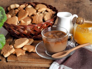 A cup of tea with milk and homemade butter cookies. Still life on a brown background.