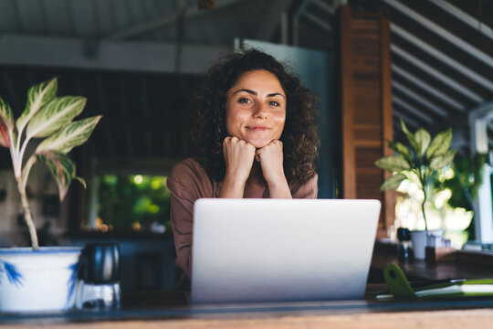 Portrait of skilled female programmer with modern laptop computer looking at camera during remote working at cafe terrace, millennial woman with digital netbook posing during freelance distance job
