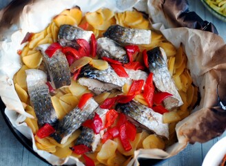 Chum salmon baked with potatoes and vegetables in the kitchen oven using baking paper. Healthy homemade delicious food.