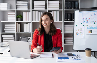 Beautiful businesswoman in red suit working in modern office room.