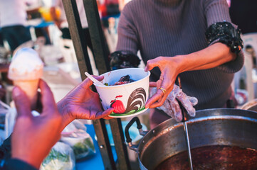 Fototapeta premium Volunteers serving hot meals to hungry migrants: humanitarian aid concept.