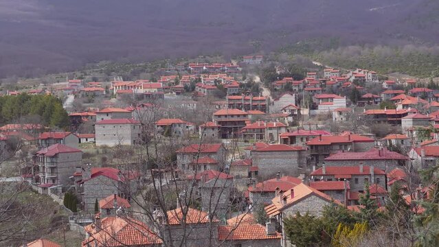 Mountain Lodges traditional village settlement with stone-built houses and red tile rooftops in Agios Athanasios, Greece.