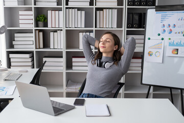 Office woman stretching body for relaxing while working with laptop computer at her desk, office lifestyle.