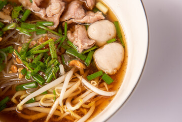 Noodles with pork and pork balls with soup Thai style in white bowl