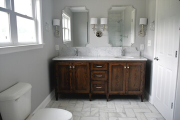 Naklejka na ściany i meble Clean bright bathroom with dark wood vanity and white marble sinks in a new home or after a remodel