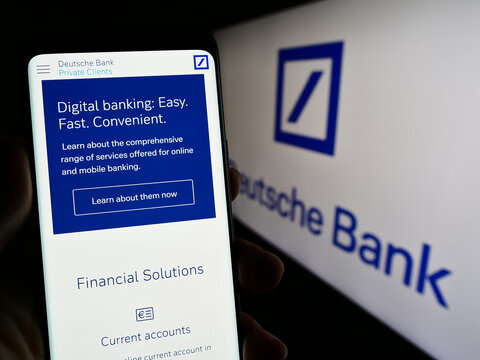 Stuttgart, Germany - 03-25-2023: Person holding smartphone with web page of German financial company Deutsche Bank AG on screen in front of logo. Focus on center of phone display.