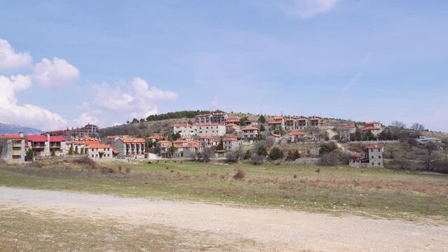 Mountain Lodges traditional village settlement with stone-built houses and red tile rooftops in Agios Athanasios, Greece.
