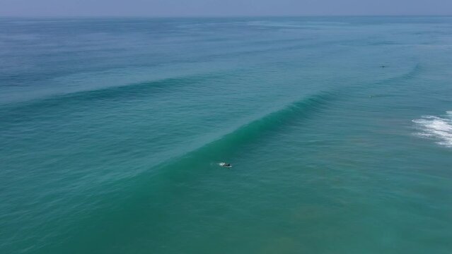 Pro surfer riding a long wave in El Palmar, Spain. Drone video of a surfer doing an aerial 360 trick on surfboard.