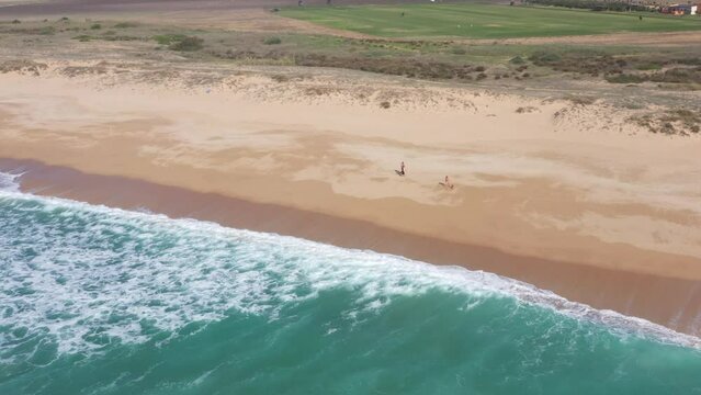 Aerial drone view of surfer sitting on his board watching the waves coming by.
