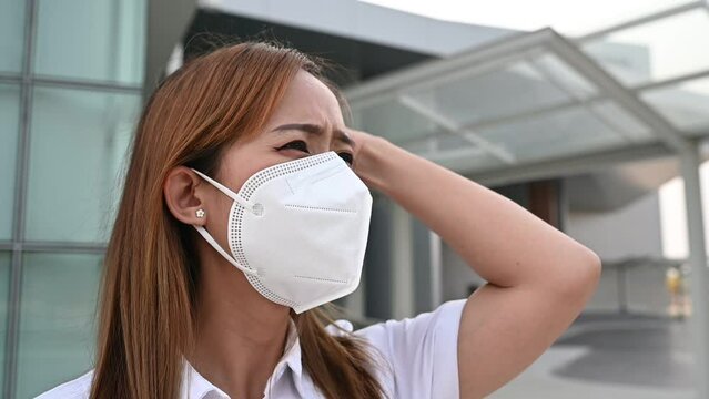 Asian woman wear N95 mask for protect dust pm 2.5,ecology concept. Allergy, headache. air danger in city.