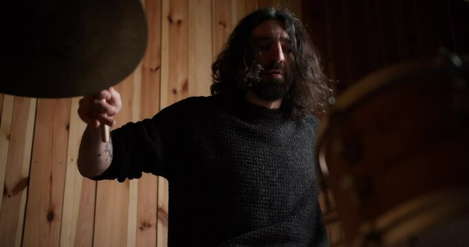 Male musician with drumsticks playing drums and cymbals at studio