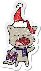 distressed sticker cartoon of a cat with christmas present wearing santa hat