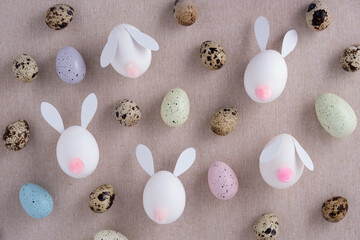 Pattern made of diy rabbits and quail eggs on fabric background. Easter eggs.