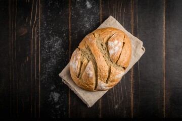 bread on wooden table, delicious freshly baked bread resting on a kitchen towel on a black wooden table