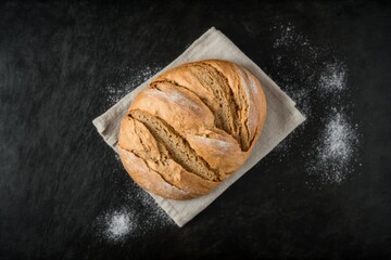 freshly baked bread on top of tea towel on black stone table