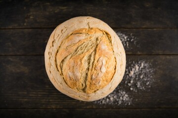 delicious freshly baked bread on kitchen towel on dark brown wooden table