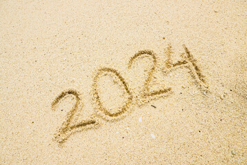 Handwriting year 2024 on sand on beach. 2024 written on a sandy beach, concept for new year greeting cards and calendars. Years Sand Writing.