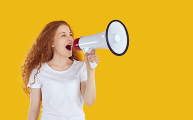 Marketing, seasonal sales and discounts. Expressive girl using megaphone to announce discounts and sales isolated on yellow background. Red-haired curly girl in white t-shirt speaks into loudspeaker. - obrazy, fototapety, plakaty