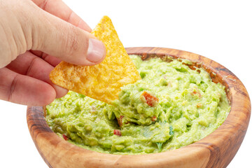 Dipping corn chips into guacamole on white background.