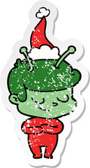 friendly distressed sticker cartoon of a spaceman wearing santa hat