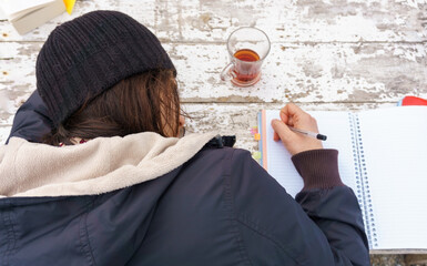 Young woman falling asleep while working and taking notes on wooden table background. Top or above view of a lady writing memories and keeping diary concept.