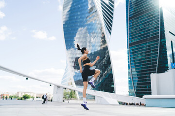 Athletic woman running on street near modern building