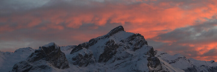 Obraz premium Bright lit clouds over snow covered mountains in Switzerland.