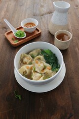 wonton soup dish with celery, spring onions and chili sauce