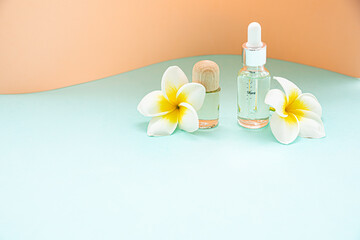 A bottle of essential oils and tropical flower on a white background. Skin and body care concept.