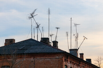 Many old television antennas on the roof of an old house