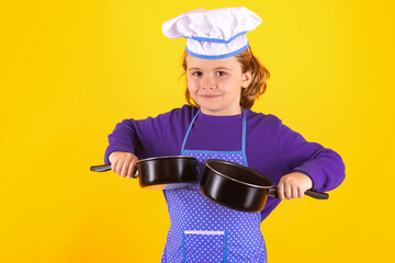 Kid chef cook with cooking pot stockpot. Child chef cook. Child wearing cooker uniform and chef hat preparing food, studio portrait.