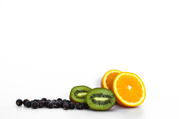 Kiwi, orange and black currants on light background