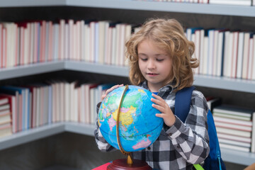 Explorer and discovery. School kid pupil looking at globe in library at the elementary school. World globe. School kid 7-8 years old with book go back to school. Little student. Education concept.