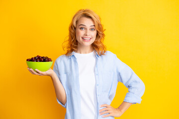 Portrait of woman with cherries on yellow studio isolated background.