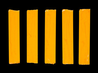 5 vertical pieces of orange adhesive tape isolated on a black
