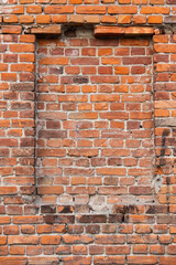 Red brick wall with a window that is blocked by bricks, an old house close-up. Building exterior