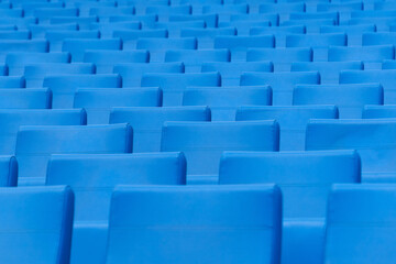 Seats at the stadium. Empty seats in the stands of the arena or auditorium. Rows of blue seats without spectators.