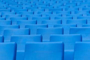 Fototapeta premium Seats at the stadium. Empty seats in the stands of the arena or auditorium. Rows of blue seats without spectators.