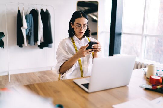 Focused woman using cellphone in atelier