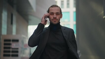 Closeup of smiling man business man in dark gray golf and suit talking by phone walking at city street, slow motion 4k stock footage, trekking camera shot - Powered by Adobe