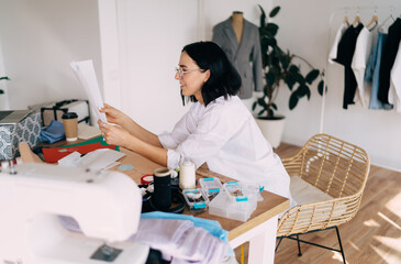 Young female designer looking through paper sketches