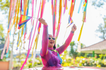 Happy Asian woman support LGBT pride parade in car. with Rainbow of LGBTQ or LGBTQIA.