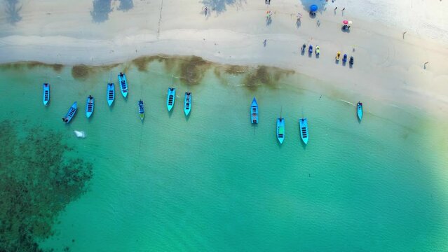 From above, visitors can see a vibrant mixture of bright umbrellas, and sunbathers lounging in the sun. The clear blue water is perfect for swimming, snorkeling. (Haad Rin, Koh Phangan, Thailand)
