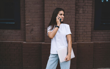 Woman speaking on smartphone holding netbook