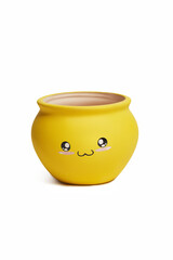 Close-up shot of an empty yellow ceramic pot for flowers. A funny flower pot with a smiley face is isolated on a white background. Front view.