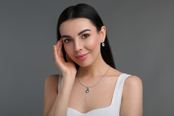Beautiful young woman with elegant jewelry on dark grey background