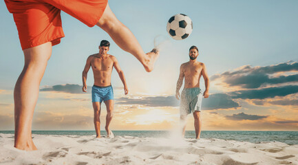Friends playing football on beach during sunset, low angle view