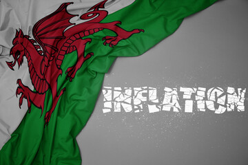 waving colorful national flag of wales on a gray background with broken text inflation. 3d illustration