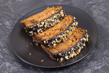 Pieces of zucchini dough with nuts and raisins on black plate